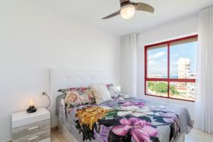 a bedroom with a bed with a floral bedspread and a window at Torre Mar Muchavista in El Campello +23 photos