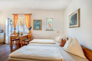 a bedroom with two beds and a table and a desk at Weingut Lieselehof Apt Vitis in Caldaro