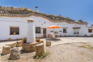 a white building with an orange umbrella and a patio at La Higuera in Benalúa de Guadix