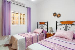 two beds in a room with purple curtains at Casa Chiqui - solo familias in Conil de la Frontera +20 photos