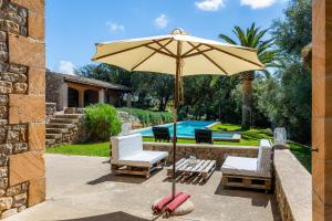 a patio with an umbrella and two chairs and a pool at Son Calletes in Artá