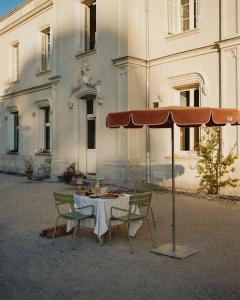 a table with chairs and an umbrella in front of a building at CHB - Château de la Haute Borde in Rilly-sur-Loire