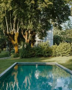 a swimming pool in a yard with trees and a house at CHB - Château de la Haute Borde in Rilly-sur-Loire