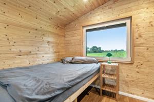 a bed in a wooden room with a window at Naturpur Tinyhouse in Osterrade