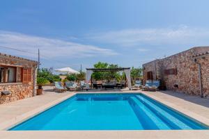 a swimming pool in front of a stone house at Hortet in Campos