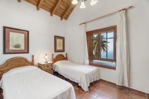 two beds in a white room with a window at El Ciruelo in Valverde