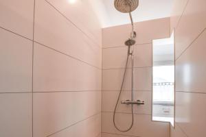 a shower in a bathroom with white tiles at Ferienwohnung zum Krummholz in Fischerbach +5 photos