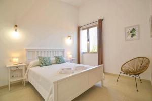 a bedroom with a white bed with a chair and a window at Caleu in Binissalem +30 photos