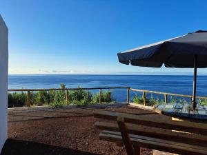 a view of the ocean with a bench and an umbrella at Baía do Porto das Lajes in Lajes das Flores