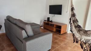 a living room with a couch and a chair and a tv at Baía do Porto das Lajes in Lajes das Flores