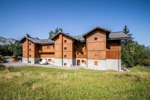 a large wooden building with a field in front of it at Appart Cosy 3 étoiles in Arâches-la-Frasse