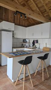a kitchen with white cabinets and a counter with two bar stools at Baía do Porto das Lajes in Lajes das Flores