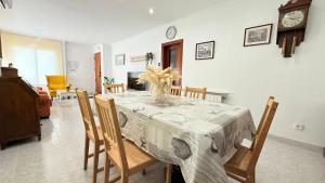 a dining room with a table with chairs and a clock at Bruc Apartment Beach in Canet de Mar