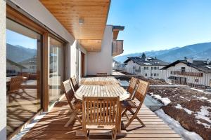 a wooden table and chairs on a balcony with mountains at Villa Helena - Panorama Dolomiti in Cavalese