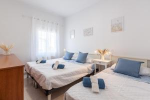three beds in a room with blue pillows on them at Bruc Apartment Beach in Canet de Mar +20 photos