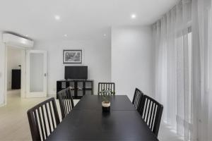 a dining room with a black table and chairs at T2 Furadouro 30m from the beach in Ovar