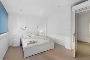 a white bedroom with a white bed and white walls at T2 Furadouro 30m from the beach in Ovar