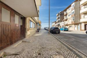 a street with cars parked on the side of a building at T2 Furadouro 30m from the beach in Ovar