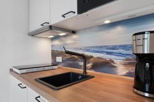 a kitchen with a sink and a painting on the wall at Ferienwohnung Alte Liebe in Cuxhaven