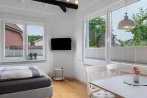 a living room with a bed and a table and windows at Ferienwohnung Alte Liebe in Cuxhaven