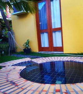 una pequeña piscina frente a una casa con puerta roja en Sossego de Jaua en Camaçari