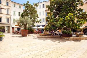 a courtyard with trees and tables and buildings at La Maison Méditerranéenne in La Ciotat