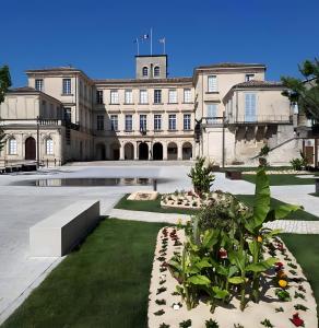 a large building with a courtyard with plants at Sous Le Tilleul - 3 personnes in Valréas