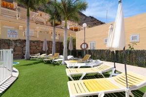 a group of lounge chairs and umbrellas on a lawn at Mangueros Suite 18 Puerto de Mogán in Puerto de Mogán