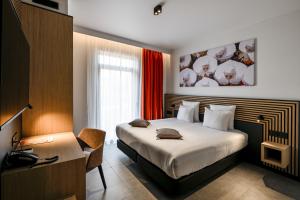 ein Schlafzimmer mit Bett und Schreibtisch mit Telefon in der Unterkunft Orange Hotel La Louvière in La Louvière + 101 Fotos