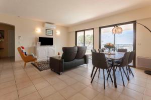 a living room with a dining room table and chairs at Le Plein Sud Terrasse vue mer Agay in Saint-Raphaël