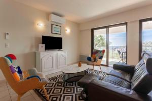 a living room with a couch and a tv at Le Plein Sud Terrasse vue mer Agay in Saint-Raphaël