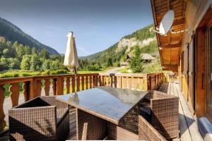 a wooden balcony with a table and an umbrella at Chalet Chocolat - 10 pers - Châtel in Châtel