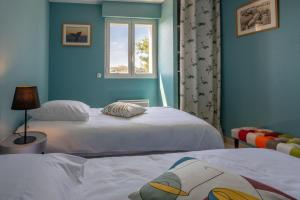 two beds in a room with blue walls and a window at Le Plein Sud Terrasse vue mer Agay in Saint-Raphaël