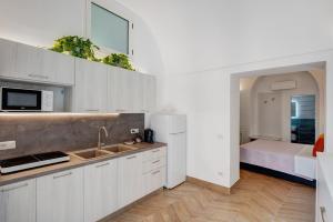 a kitchen with white cabinets and a sink and a bed at Lubrense Signature Suites in Massa Lubrense