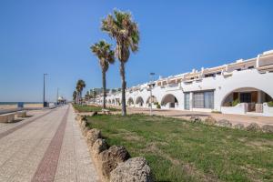 a street in front of a white building with palm trees at Primera Linea en Matalascañas in Matalascañas