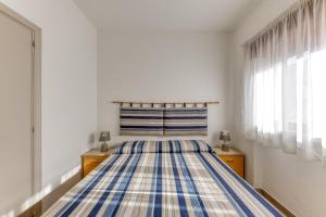 a bedroom with a striped bed with two dressers and two windows at Franza 2 in Torre San Giovanni Ugento