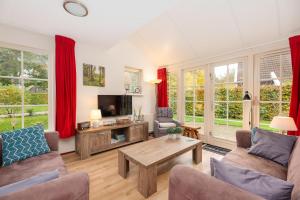 a living room with red curtains and a coffee table at Buitengoed het Lageveld 137 in Hoge-Hexel