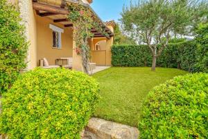 a garden with green bushes and a house at Mazzini Apartment - by And Service in Golfo Aranci