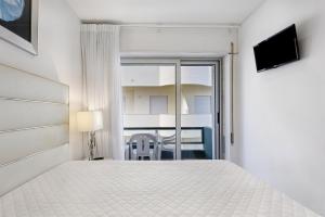 a white bedroom with a bed and a balcony at Natalina T2 in Nazaré