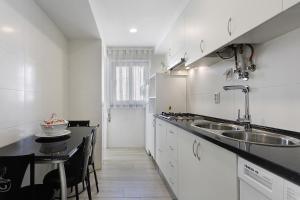 a white kitchen with a sink and a counter at Natalina T2 in Nazaré
