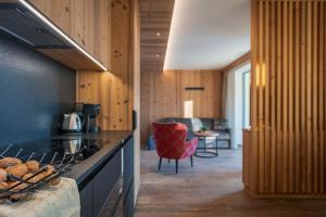 a kitchen with a stove top oven next to a living room at Arnica Alpin Lodge in Cavedago