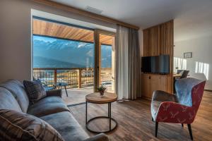 a living room with a couch and chairs and a large window at Arnica Alpin Lodge in Cavedago