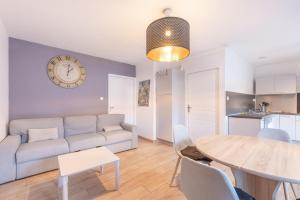 a living room with a couch and a table and a clock at Chalets De L’arriutort 2 - Laruns in Laruns