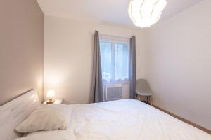 a bedroom with a white bed and a window at Chalets De L’arriutort 2 - Laruns in Laruns