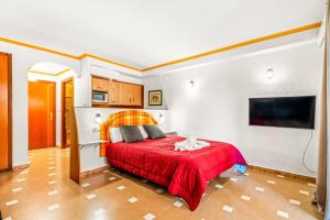 a bedroom with a red bed and a flat screen tv at Unique hotel apartment 1-2 in Torrevieja