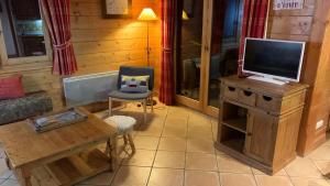 a living room with a tv and a chair at Appartement Airelles B19 in Levassaix