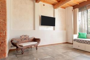 a living room with a chair and a tv on the wall at Sunflowers Dimora in Cascina