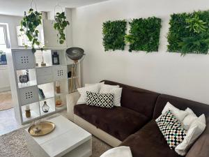 a living room with a brown couch and plants on the wall at Ruhige Ferienwohnung in Appenweier