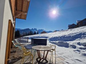 a table and chairs on a deck in the snow at Germain Ski Lodge in La Toussuire