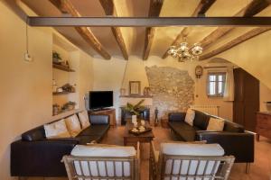 a living room with leather furniture and a stone wall at Cal Cabrer in Sant Jaume dels Domenys